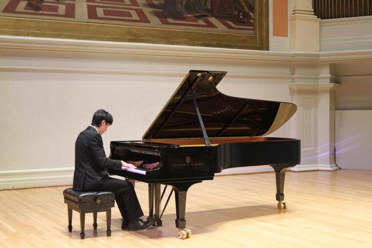 Student playing piano on the stage of Old Cabell Hall