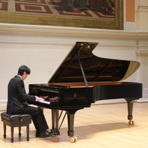 Student playing piano on the stage of Old Cabell Hall
