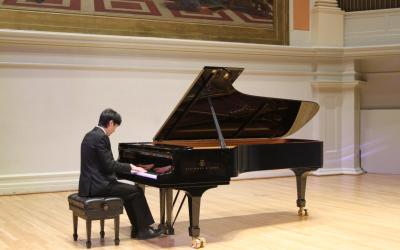 Student playing piano on the stage of Old Cabell Hall