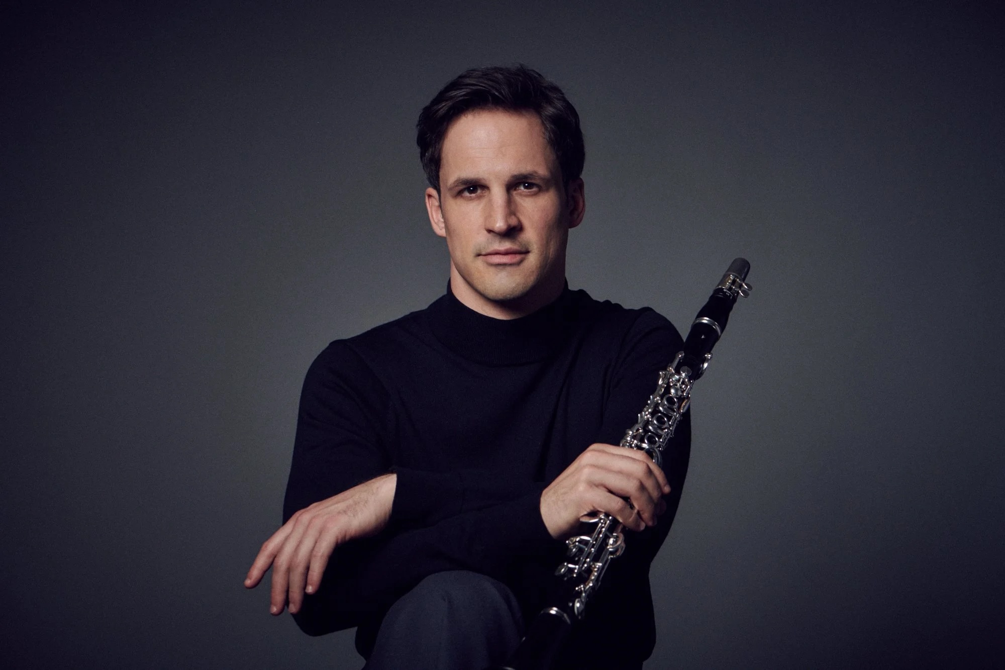 Andreas Ottensamer, holding clarinet, with monochrome background